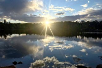 sunset over a lake with clouds mirrored in the water
