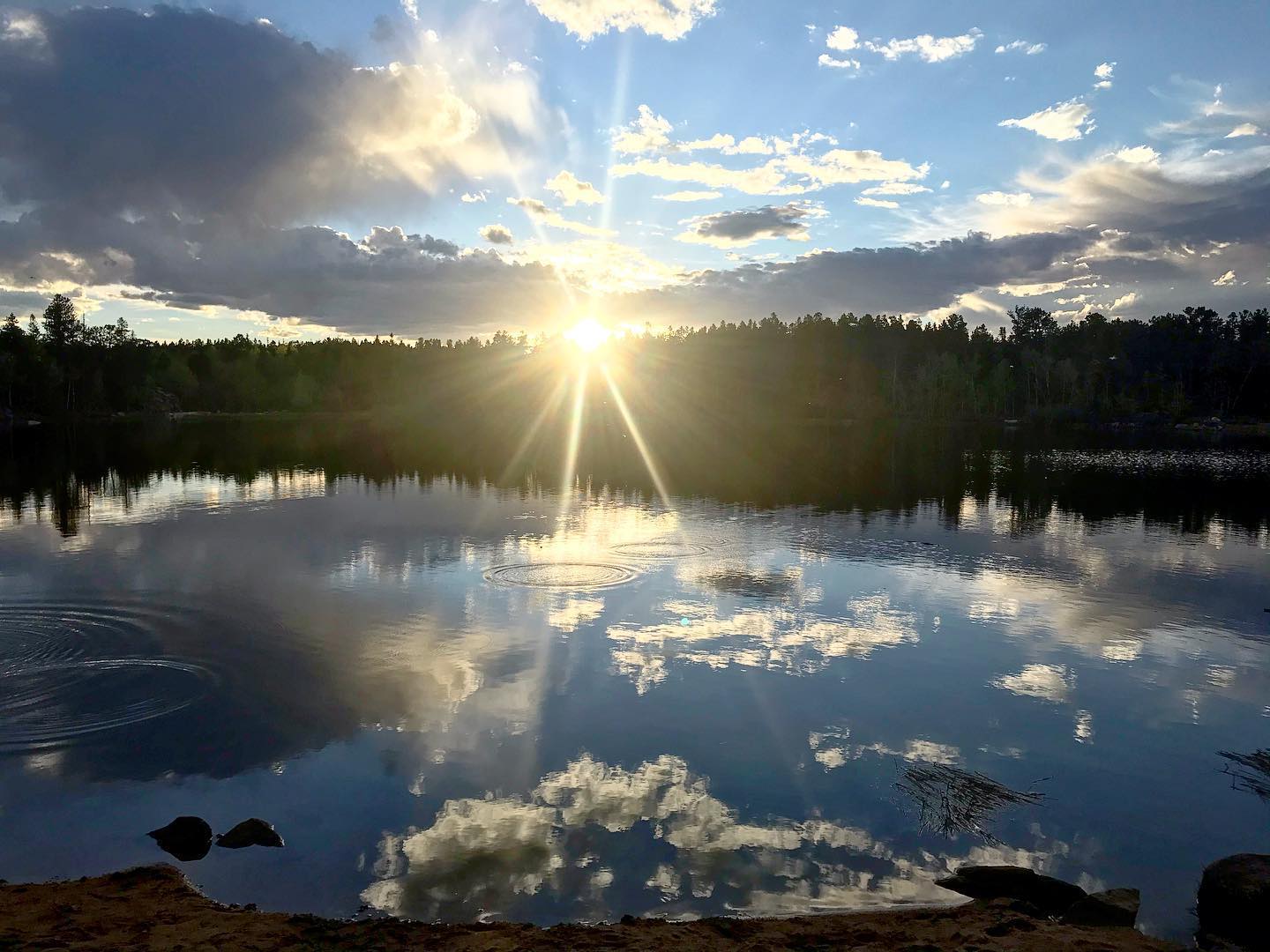 sunset over a lake with clouds mirrored in the water